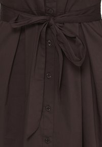 Robe en tissu marron foncé avec fermeture à boutons sur le devant et ceinture assortie nouée en nœud au centre.