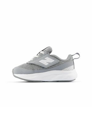Zapatilla New Balance en gris y blanco con tela de malla, suela acolchada, cordones y tira de suspensión en el talón, vista lateral sobre fondo blanco.