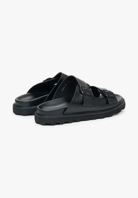Černé sandály vyrobené z hladké kůže, s designem křižujících se pásků a nastavovacími sponami na strukturované gumové podrážce.