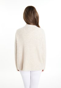Maglione a maglia beige chiaro con una vestibilità comoda, texture a coste e maniche lunghe. Presenta un collo arrotondato e spacchi laterali all'orlo.
