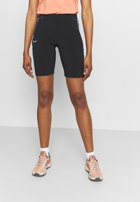 Černé atletické šortky s přiléhavým střihem, vyrobené z pružného materiálu. Mají kapsy na zip a malý bílý logo na stehně.