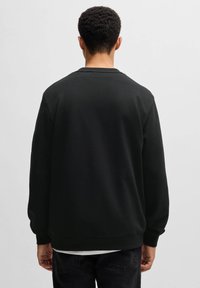 Svart sweatshirt med rund halsringning, långa ärmar och ribbade muddar. Har en slät yta och en enkel design, sedd bakifrån.