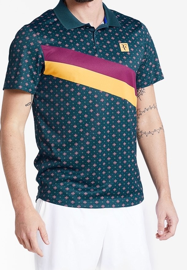 Polo à manches courtes de couleur bleu sarcelle, avec un motif floral, une bande diagonale violette et jaune sur la poitrine, et un petit logo sur le col.