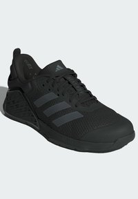 Chaussure de sport noire avec tige en maille, trois rayures gris foncé et semelle en caoutchouc texturée. Comprend une technologie de gestion de la chaleur et un col rembourré.