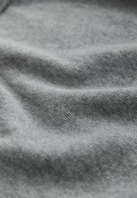 Tissu gris à surface douce et texturée, présentant un motif tissé subtil et des plis légers, indiquant sa nature flexible et souple.