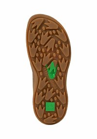 Suela de goma marrón con un patrón de agarre texturizado que presenta estampados de hojas y del talón. Logo de rana verde y letras de la marca visibles cerca del talón.