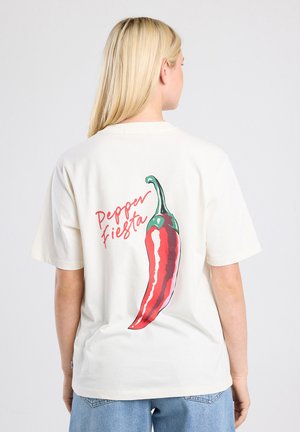 Crème-kleurig t-shirt met een grote rode chilipeperafbeelding en de tekst "Pepper Fiesta" in het roze, op de achterkant. Korte mouwen, ontspannen pasvorm.