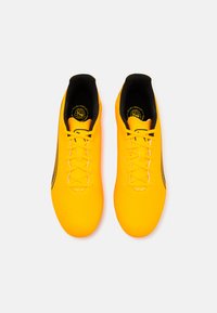 Scarpe da calcio gialle brillanti con superficie testurizzata, dettagli neri e lacci. Presentano una vestibilità aderente con interno imbottito e motivo di trazione.