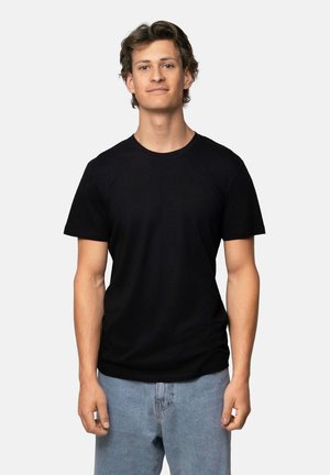 Svart bomullst-shirt med rund halsringning och korta ärmar, i kombination med ljusblå denimjeans. Enkel, slät tygstruktur.