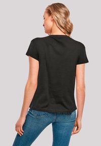 Black cotton t-shirt with short sleeves, a round neckline, and a relaxed fit. Visible stitching and smooth texture. Worn with blue jeans.