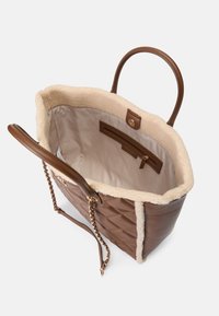 Sacola tote de couro castanho acolchoada com forro em pele creme, alças duplas castanhas e detalhe em corrente. O interior possui um bolso com fecho e um tecido suave.