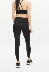 Svarta träningsleggings och matchande sportbehå. Leggings är kroppsnära med en slät yta, och behån har korsande band.