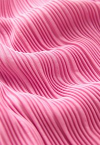 Rosa tyg med vertikala veck, mjuk textur och en slät finish, vilket skapar ett vågformigt mönster genom materialet.