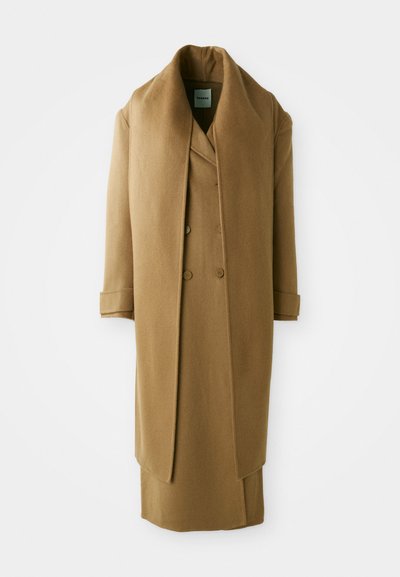 Pikk pruun villane mantel, millel on ülepaisutatud krae, topelt-kliendiga esiosa ja laiad varrukad. Omab sujuvat, tekstuurset viimistlust.