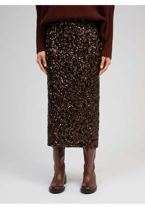Jupe midi à sequins marron portée avec un pull marron foncé et des bottes en cuir marron mi-mollet sur un fond neutre.