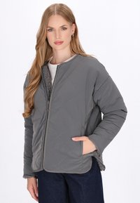 Grau gesteppte Jacke mit Reißverschluss vorne, flauschigem Fleecekragen und Seitentaschen. Sie verfügt über diagonale Nähte und einen leicht oversized Schnitt.