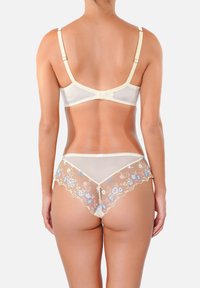 Ensemble de lingerie couleur crème avec des dents en tulle transparent brodées de fleurs et un soutien-gorge assorti. Bretelles ajustables et détails en dentelle délicate.