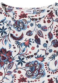 Tissu blanc avec des motifs floraux et feuillus bleus, roses et bordeaux, doté d'un col rond et d'une étiquette de marque "CECIL" au niveau du col.