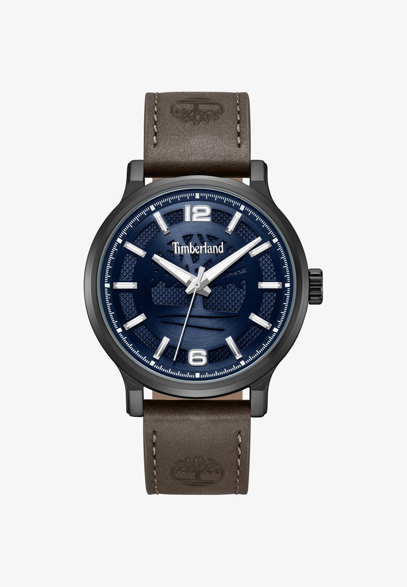 Montre Timberland avec cadran texturé bleu, index argentés, aiguilles blanches, boîtier noir et bracelet en cuir marron embossé du logo arbre.