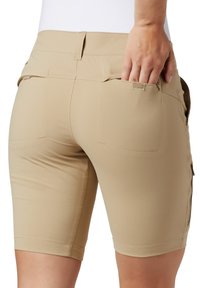 Pantaloni corti elasticizzati beige con un design aderente, tasche visibili e dettagli cuciti all'orlo. Il tessuto appare liscio e leggero.