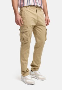Pantalones cargo beige con múltiples bolsillos laterales, hechos de una tela ligera. Presenta un corte recto y detalles de costura visibles.