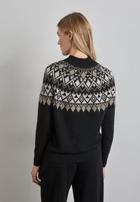 Schwarzer Pullover mit geometrischem Muster in Creme und Taupe, mit geripptem Ausschnitt und Saum, aus weichem, strukturiertem Material gefertigt.