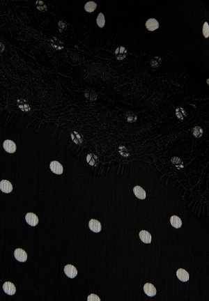 Czarna tkanina w białe kropki oraz fragment delikatnej czarnej koronki z kwiatowym wzorem.