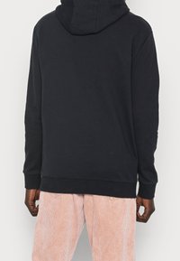 Sudadera con capucha de color azul marino, de mangas largas, con puños y dobladillo acanalados. Material de algodón suave, corte relajado, con un diseño minimalista y sin gráficos.