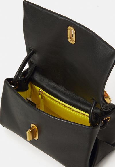 Bolso de mano de cuero negro con un cierre dorado, que presenta un interior de un brillante color amarillo y un bolsillo con cremallera. Forma simple con doble mango.