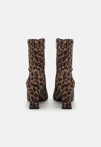 Bottes à chevilles en imprimé léopard avec un tissu texturé, fermeture éclair et talons épais. Conçues avec une silhouette ajustée et des semelles noires lisses.