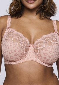 Koronkowy biustonosz w delikatnym różowym kolorze z wzorem w panterkę, z kwiatowymi koronkowymi akcentami, regulowanymi ramiączkami oraz ozdobnymi kokardkami na ramiączkach.