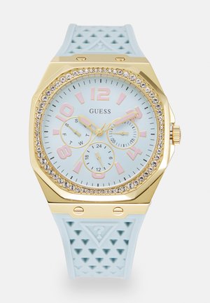 Achtkantige Uhr mit einem hellblauen Silikonuhrband, goldfarbener Lünette, hellblauem Ziffernblatt, pinken Stundenmarkierungen und Kristallakzenten.