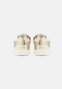 Adidași metalici aurii cu o finisare netedă, talpă din cauciuc alb și accente contrastante. Au un design low-top cu bretele ajustabile.