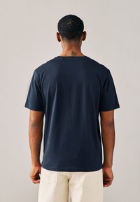 Marineblaues Baumwoll-T-Shirt mit kurzen Ärmeln, rundem Ausschnitt und lockerer Passform. Glatte Textur ohne sichtbare Logos oder Muster.