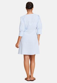 Lyseblå linikjole med en tettsittende midje, puffete ermer og kne-langt fald. Myk tekstur og enkelt design, egnet for hverdagsbruk.