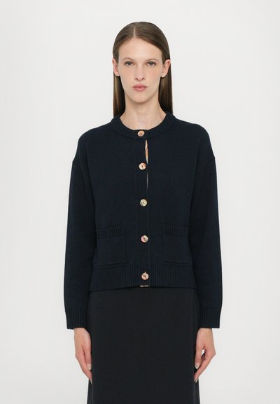 Navy knit cardigan with a round neck, featuring eight button closures, ribbed cuffs, and two front pockets. Notable buttons with patterns.