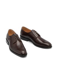 Pantofi de dress din piele maro, cu un design elegant, bot ascuțit și șase găuri pentru șireturi, așezați pe o talpă plată din cauciuc.