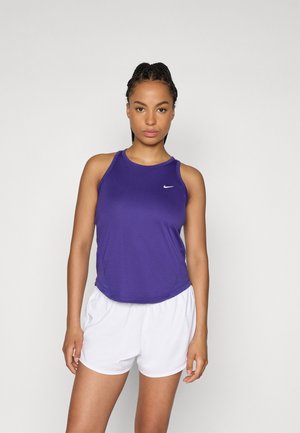 Top sin mangas de Nike en púrpura con escote redondo, diseño sin mangas y un pequeño logo blanco; combinado con pantalones cortos deportivos blancos.
