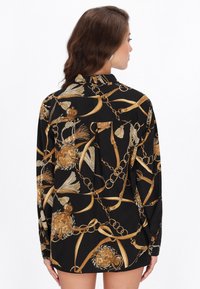 Fekete hosszú ujjú ing, arany mintával láncokból, virágokból és szalagokból. Az anyag simának tűnik; a szabás laza, gallérral.