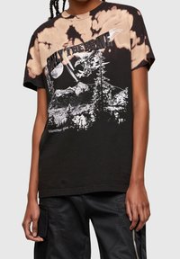 Černé tričko s batikovaným vzorem a grafickým designem, který zobrazuje hory, stromy a nápis "JEN PRO ODVÁŽNÉ" tučným písmem.