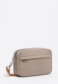 Beżowa, prostokątna torebka na ramię z srebrnym zamkiem, metalowym akcentem i pomarańczowym paskiem z logo "BIMBA Y LOLA" na przedniej kieszeni.