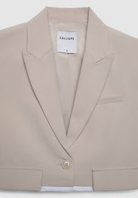 Blazer beige in tessuto liscio. Presenta un rever a lancia, chiusura con un bottone singolo e una tasca frontale. L'etichetta riporta "CALLIOPE" taglia piccola.