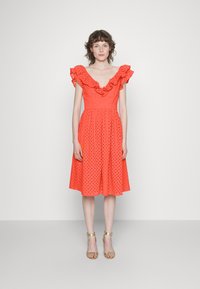 Vestido midi, em coral brilhante, com um padrão de eyelet texturizado. Apresenta um decote em V com volantes e mangas curtas. Termina com uma cintura ajustada.