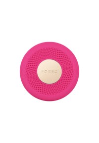 Pink silicone facial cleansing device featuring embossed dots, a circular shape, and a gold accent in the center with "FOREO" embossed.