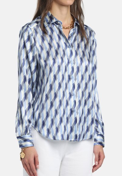 Camicia di seta con chiusura a bottoni, caratterizzata da un motivo a rombi blu e bianco. Tessuto morbido con maniche lunghe e orlo arrotondato.