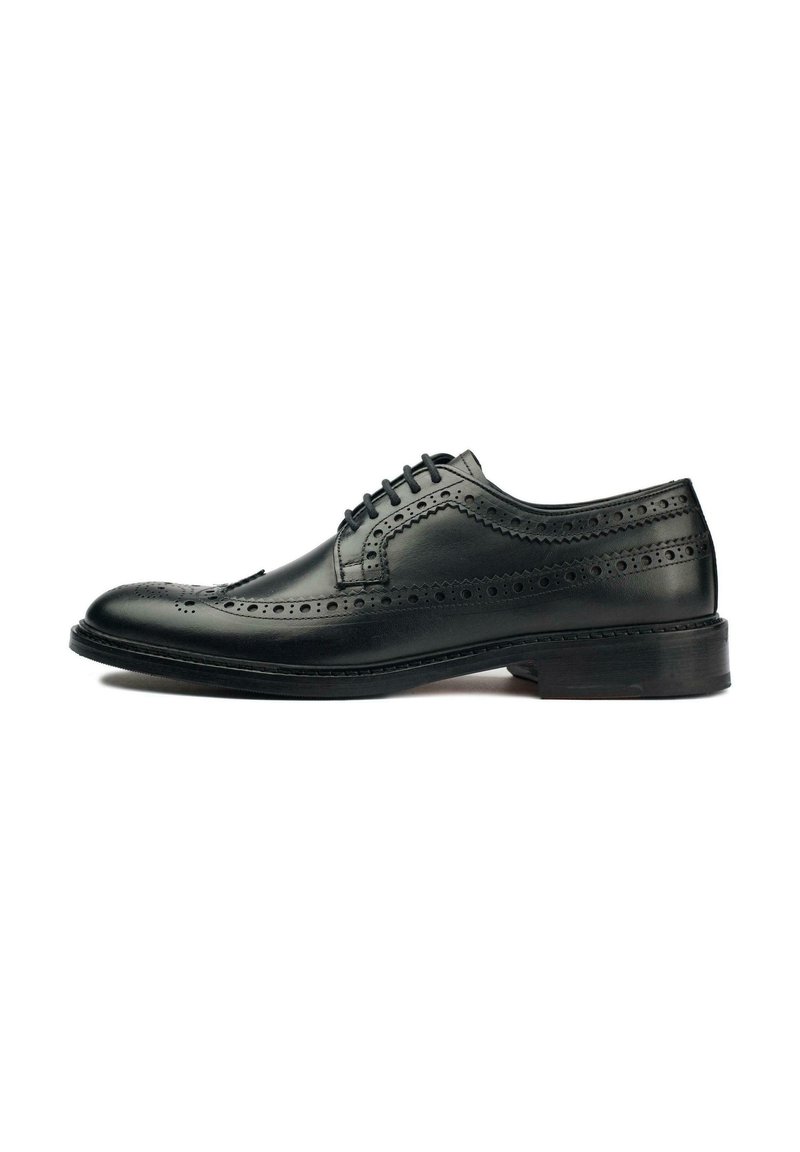 Black leather dress shoe featuring brogue detailing, lace-up design, rounded toe, and a flat rubber sole. Smooth texture with polished finish.