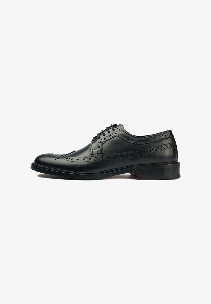 Black leather dress shoe featuring brogue detailing, lace-up design, rounded toe, and a flat rubber sole. Smooth texture with polished finish.