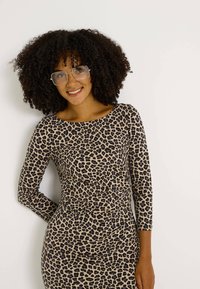 Robe imprimé léopard à coupe ajustée, manches trois-quarts, tissu doux et texture lisse sur un fond neutre.