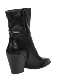 Bota de cuero negra hasta la mitad de la pantorrilla con cremallera lateral, punta afilada y tacón bloque apilado, mostrada en perfil derecho sobre fondo blanco.