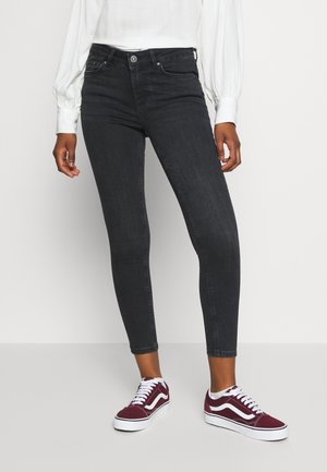Svarta skinny jeans i denim med hög midja, med fem fickor och en subtil sträck, i kombination med bordeauxfärgade Vans sneakers.